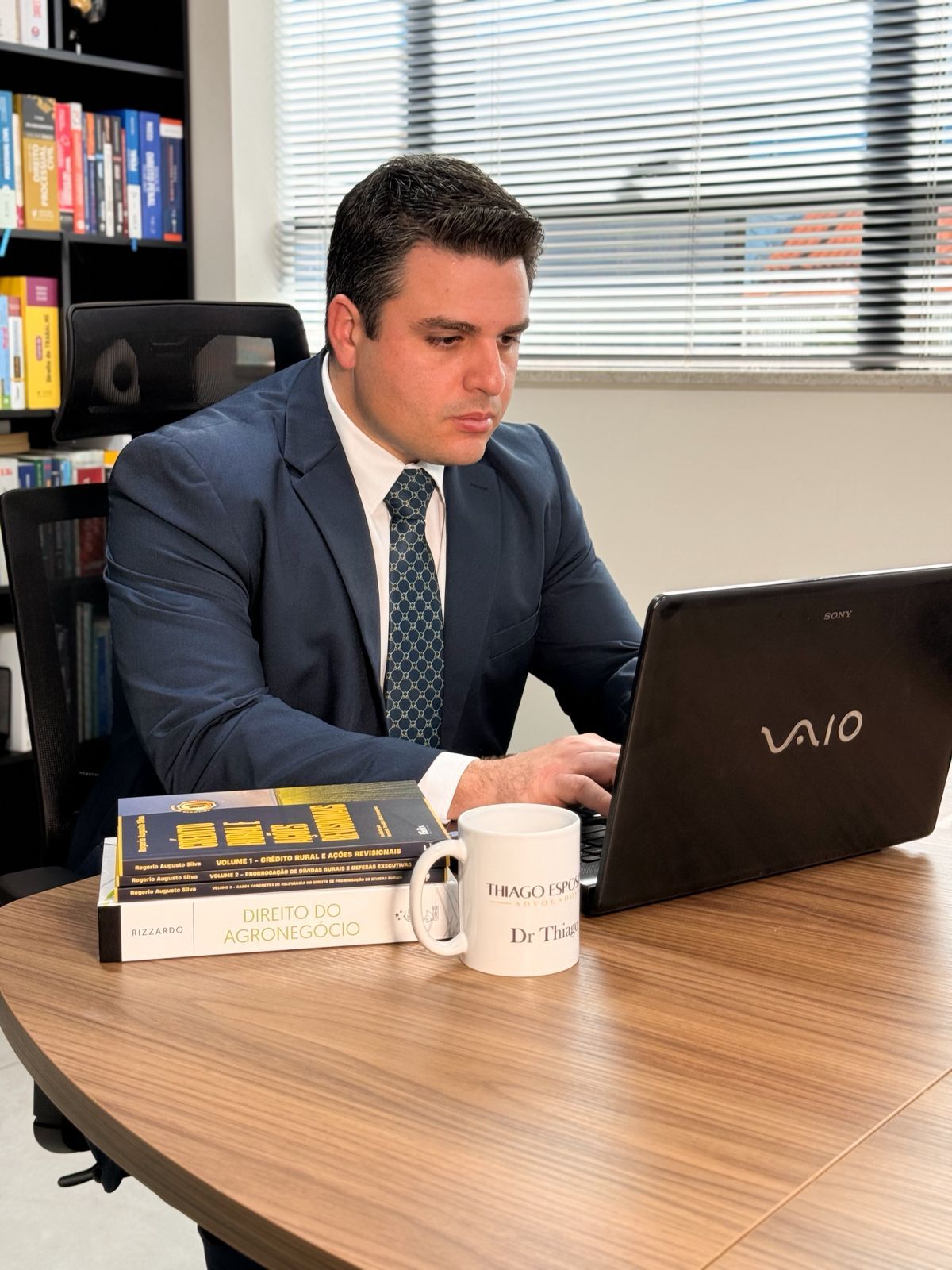 Dr. Thiago Esposito estudando um processo de crédito rural, com bibliografia especializada em Direito do Agronegócio sobre a mesa